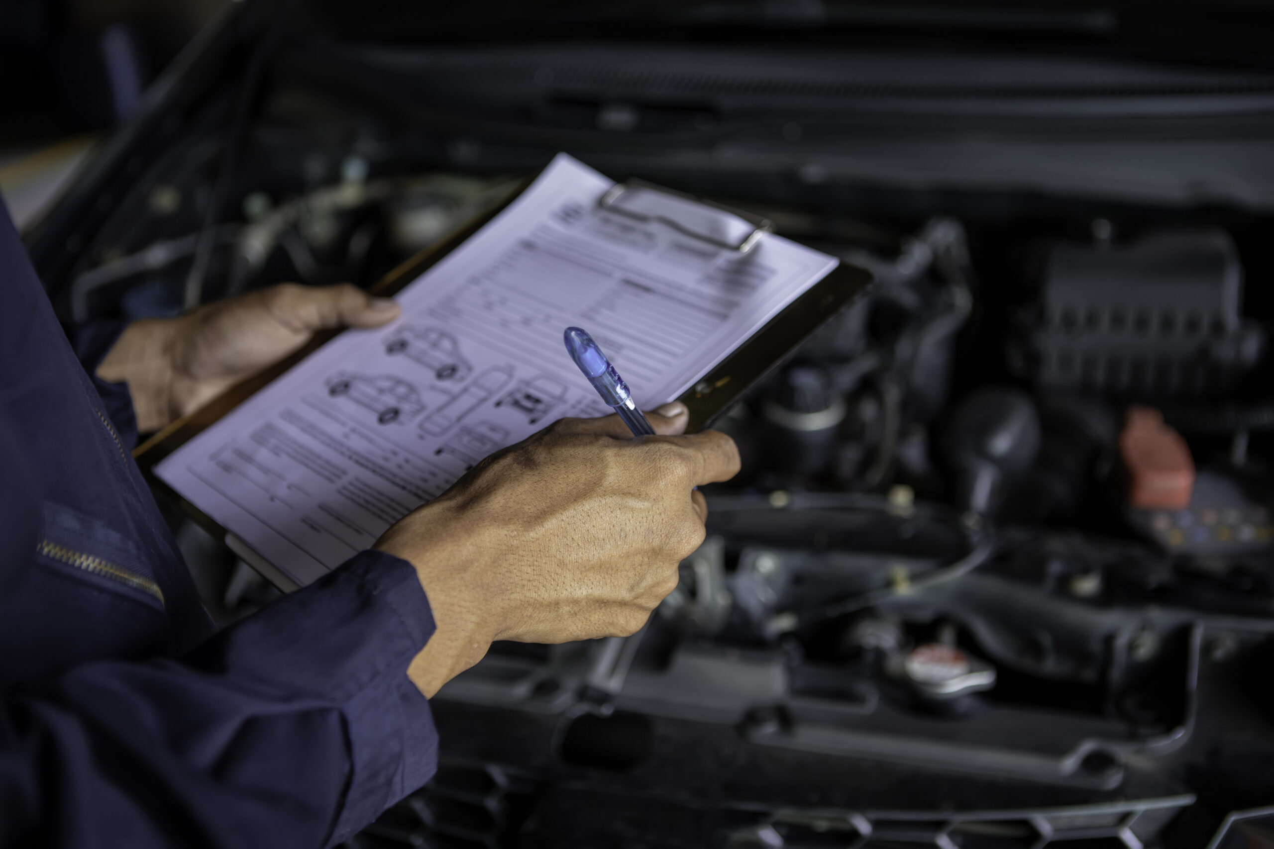 A mechanic service car in garage is check a list cars.