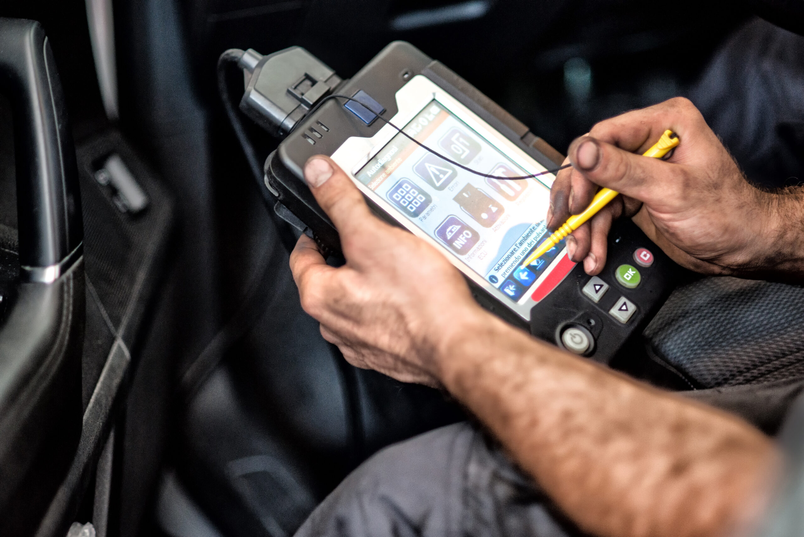 Mechanic using a car checker computer with a digital display during routine servicing and maintenance or repair work